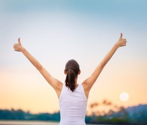 Young woman with arms in the air giving thumbs up