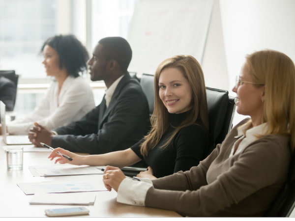 Smiling businesswoman looking at camera at corporate group meeting