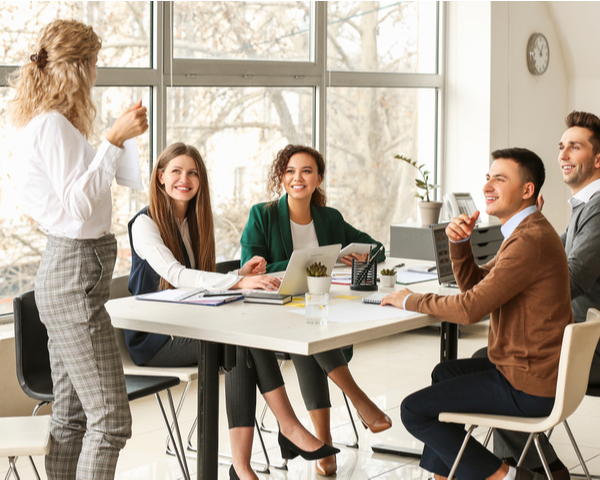 Female team leader teaching young people in office