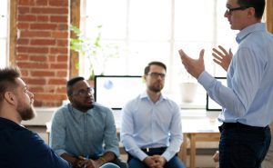 Confident male leader speaking at diverse team meeting