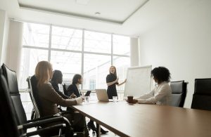 Businesswoman giving presentation to diverse partners in meeting room