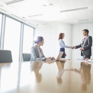 Businessman and businesswoman shaking hands in conference room